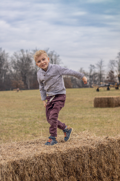 boy climbs hay bale for a picture