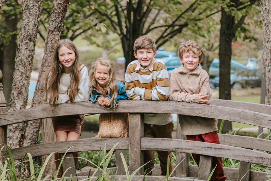 Siblings on foot bridge, smiling at camera during a Family Photography Fundraiser Event