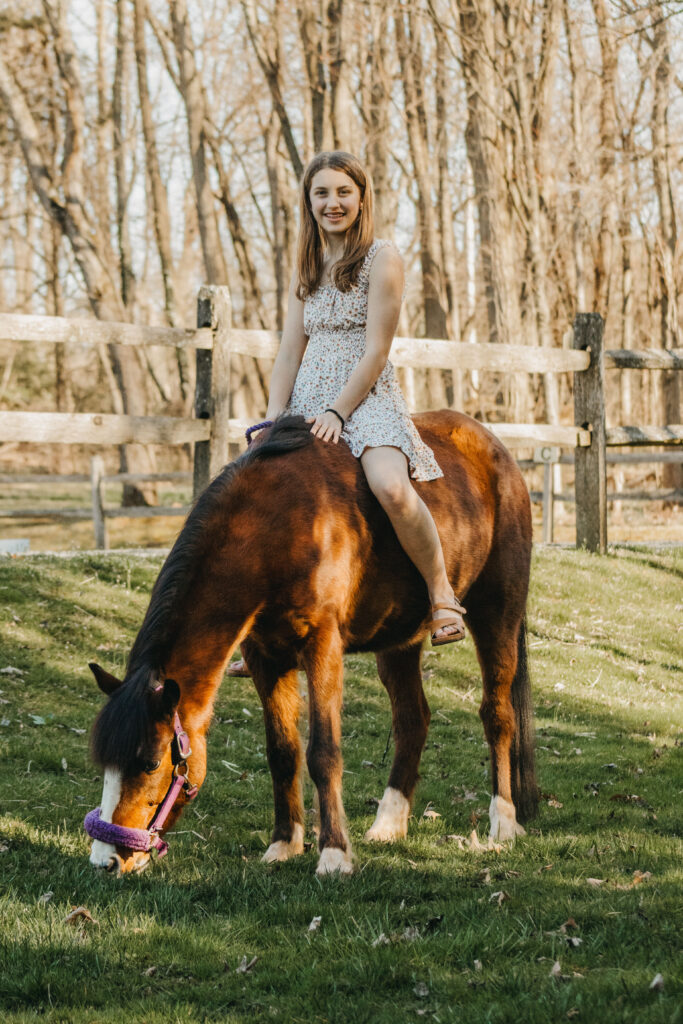 Teen girl sits on her pony during rustic family photo session in the Philadelphia Region