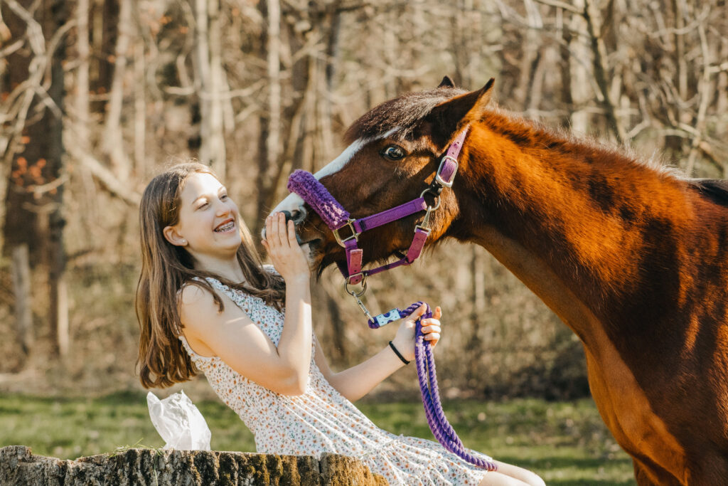 Teen girl in sun dress laughs at her pony during barn family photos in Pottstown PA