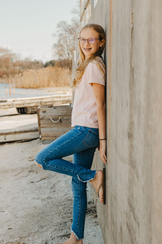 Teenage girl leans against wall at dock of Marsh Creek State Park during Mother Daughter photoshoot