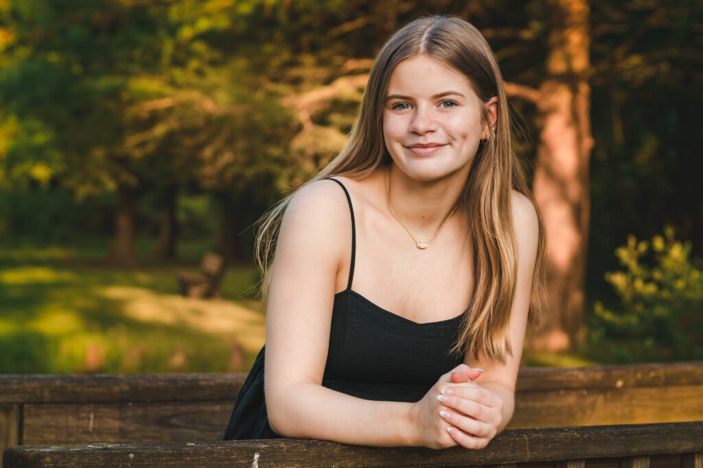 Addie leaning against the bridge railing, her face illuminated by the warm sunset light