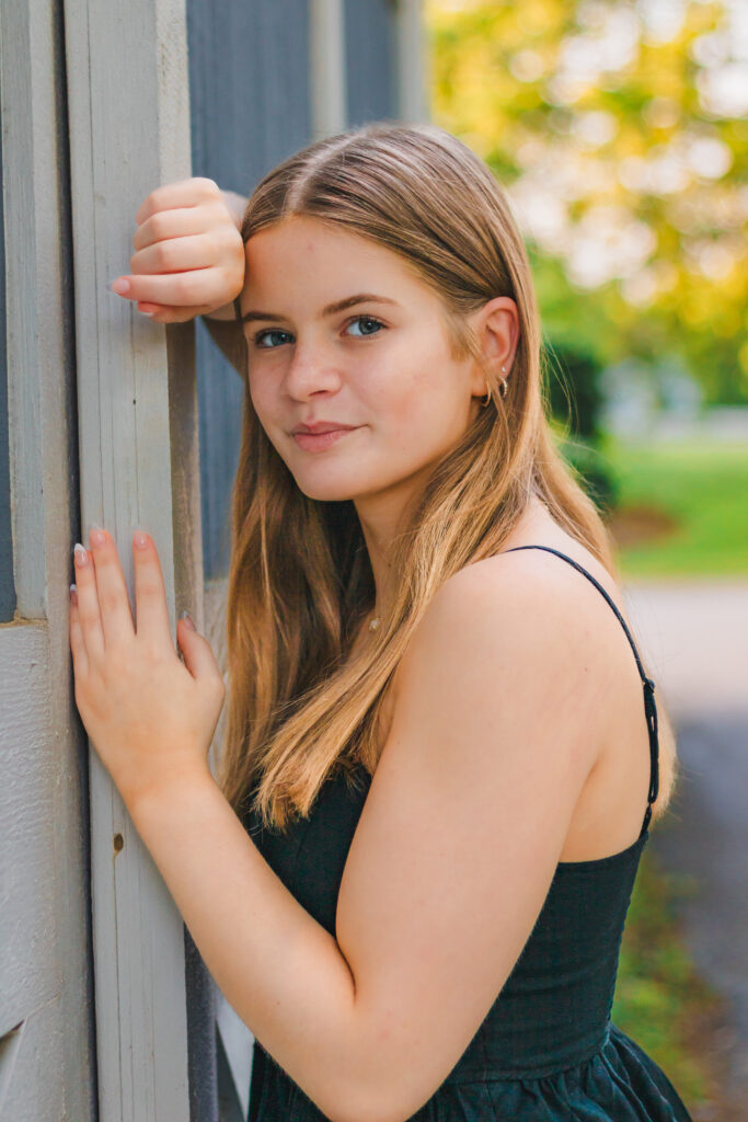 Addie leaning against the barn, her face illuminated by the warm sunset light