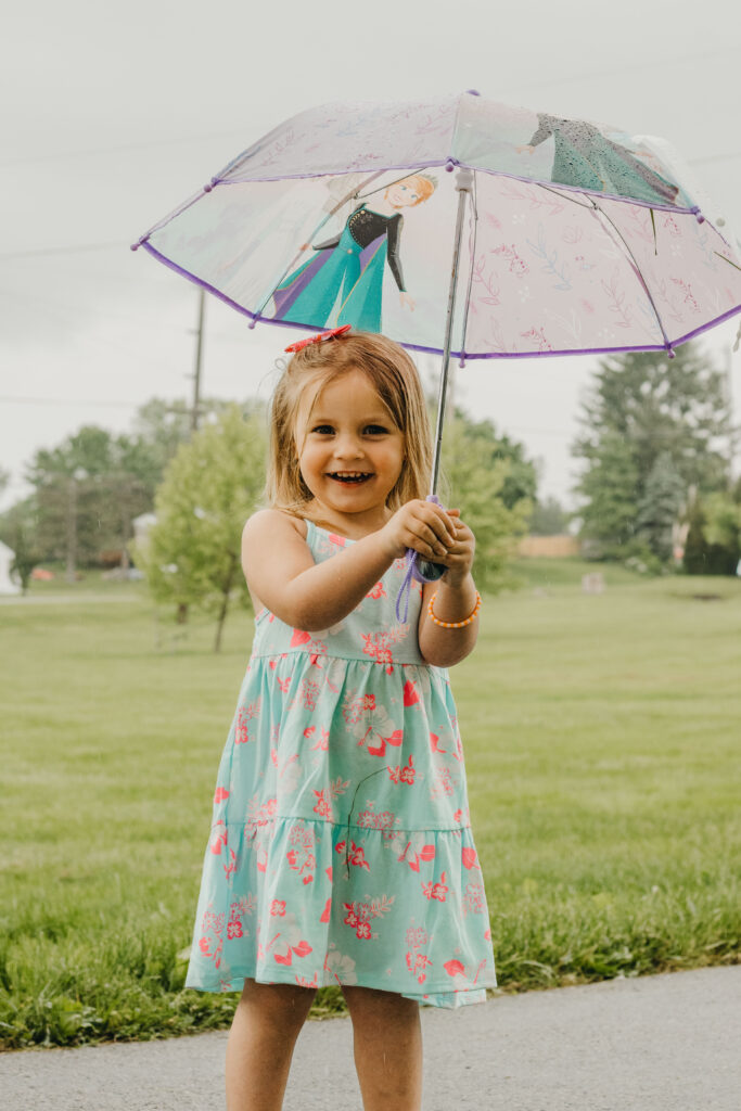 little girl laughs under umbrella at fundraiser photo session in phoenixville pa